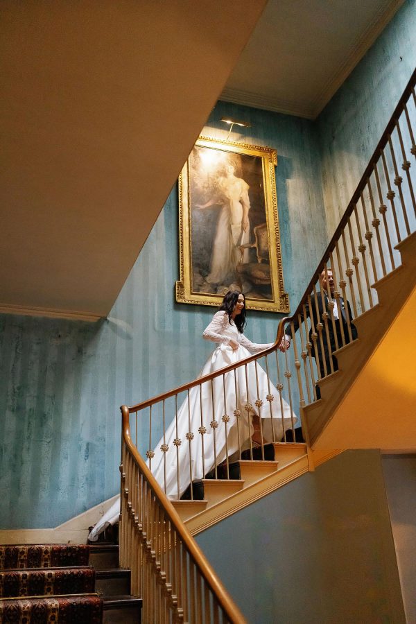 bride and groom walking up stair case in St Giles House
