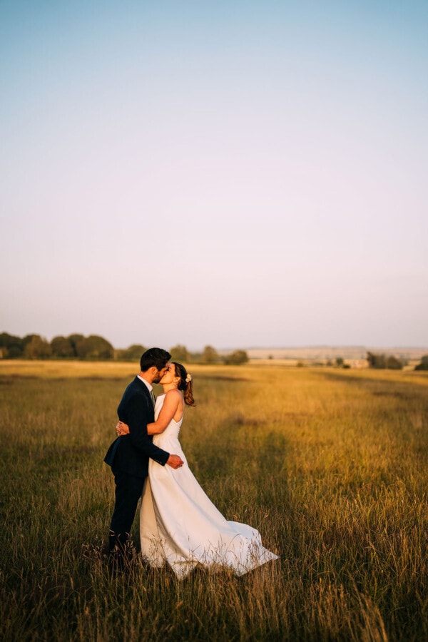 bride and groom kissing at sunset