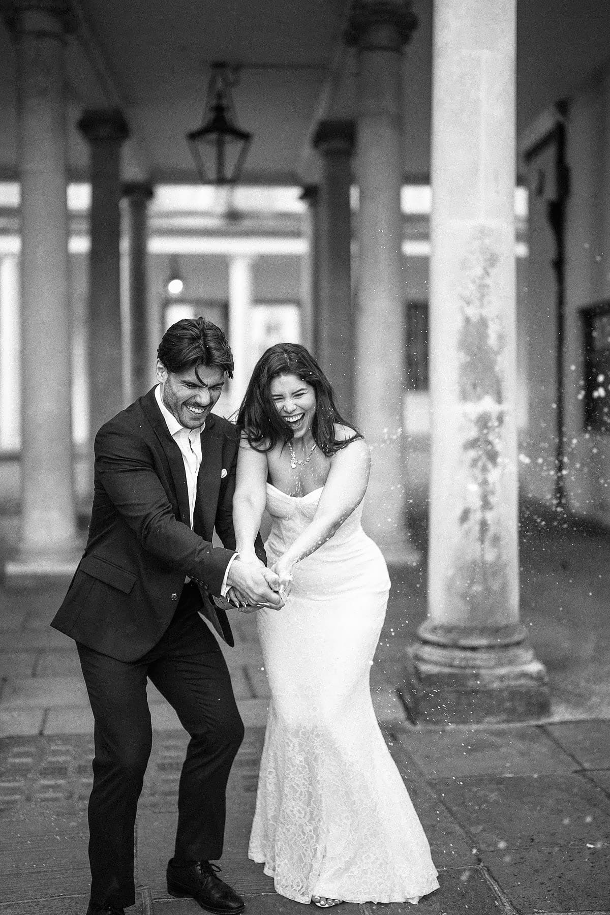 bride and groom popping bottle of champagne 