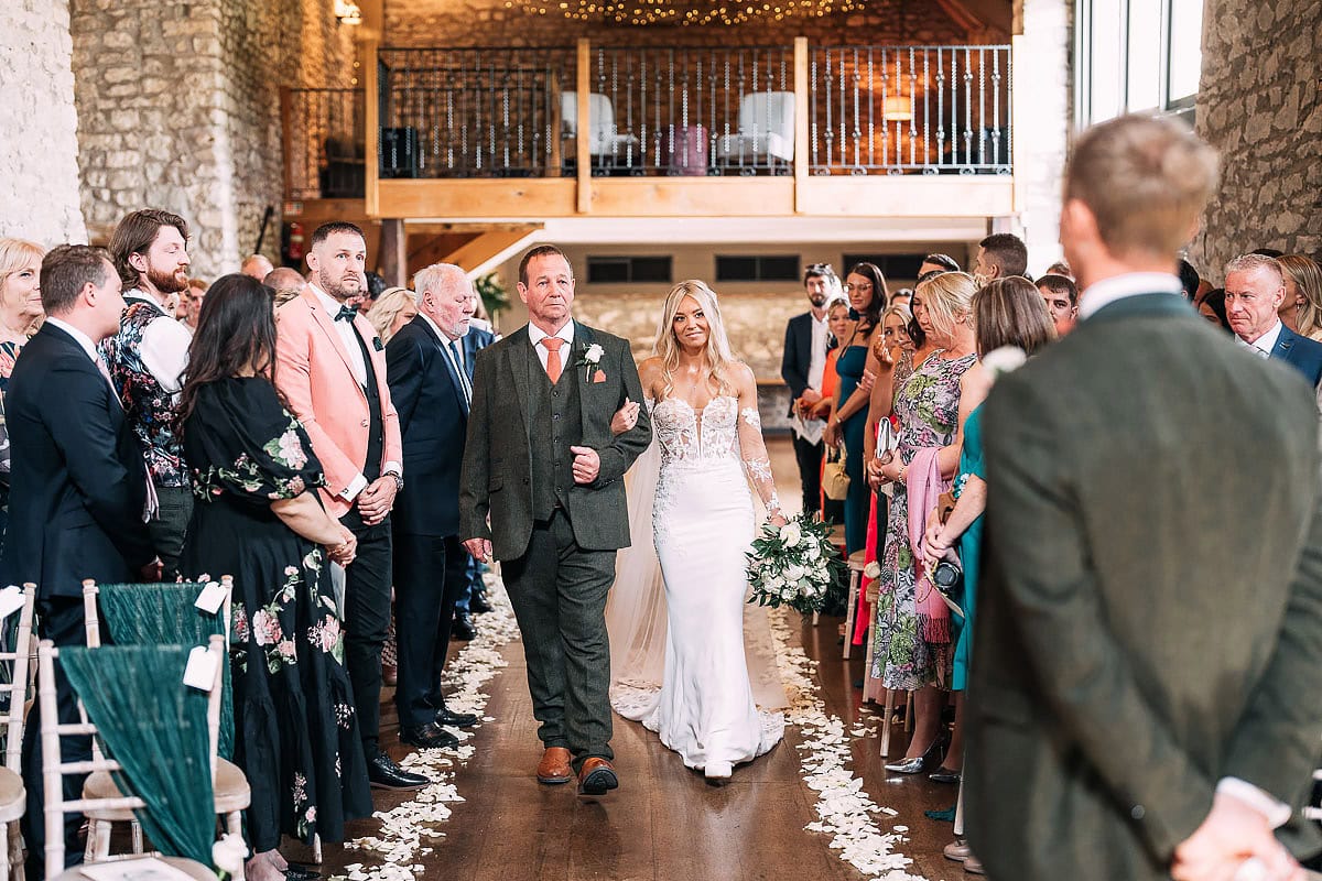 bride walking down aisle with father tythe barn