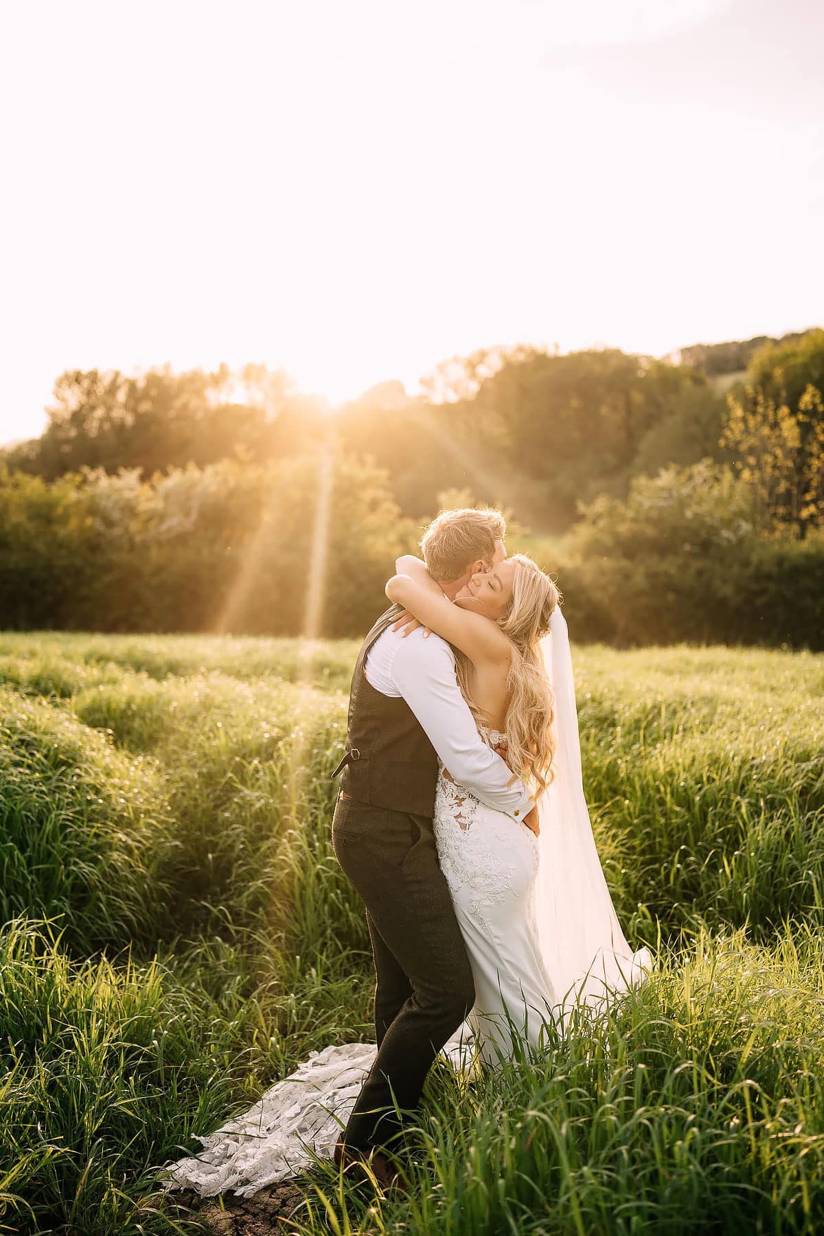 bride and groom kissing at sunset