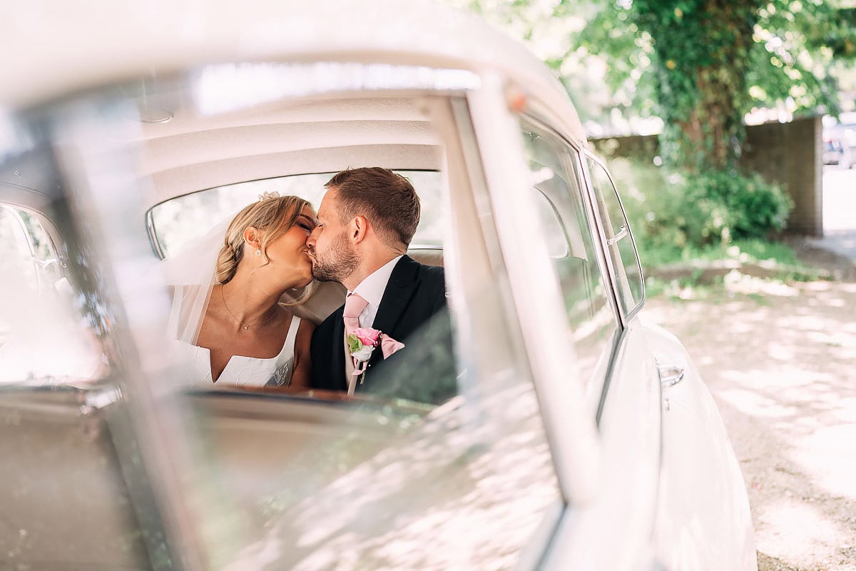 bride and groom kiss in wedding car