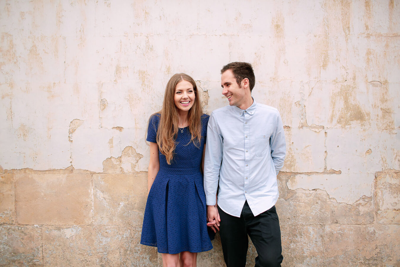 couple standing against wall laughing